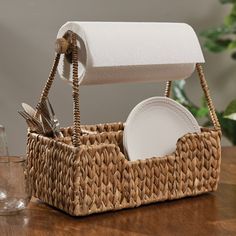 a wicker basket with utensils, plates and napkins in it on a wooden table