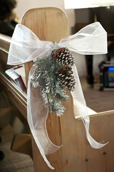 a wooden chair with a pine cone tied to it's back and white ribbon