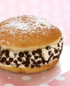 a doughnut covered in chocolate chips and powdered sugar on a pink polka dot tablecloth