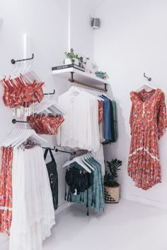 clothes are hanging on racks in a room with white walls and flooring, including an open closet