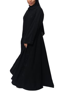 Stride with elegance and sophistication in our Rawdah Abaya. Made with buttery-soft Nida fabric, Rawdah is designed with tiny crystals for the perfect hint of glam and shimmer. The coveted A-line cut gives you a beautiful drape and that amazing Muslimah flow. Feel and look like a queen in this timeless, classy abaya. Made with ultra-soft luxurious silk Nida Open abaya with hidden buttons Black Hijab included Sleeveless dress not included Model is 5'4 and is wearing size 56 Made in Dubai Dresses Hijab, Black Hijab, A Line Cut, Open Abaya, Beautiful Drapes, Classic Black, Sleeveless Dress, Short Sleeve Dresses, Queen