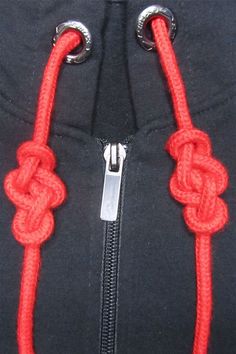 an orange rope is attached to the side of a black jacket with silver zippers