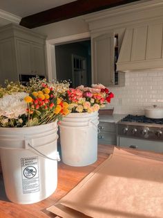 two buckets filled with flowers sitting on top of a wooden counter next to a stove