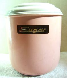 a pink sugar container sitting on top of a white towel covered floor next to a wall