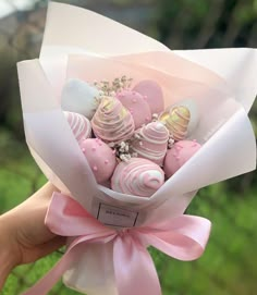 a hand holding a bouquet of pink and white chocolates