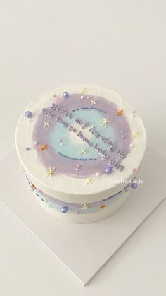 a white cake with purple icing and stars on it sitting on top of a table