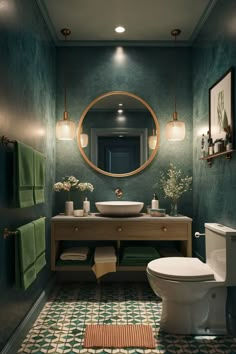 a bathroom with green walls and a round mirror on the wall above the sink,