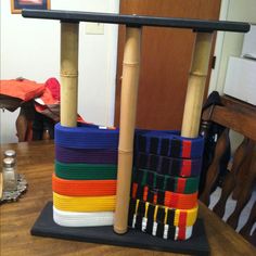 a stack of colorful belts sitting on top of a wooden table next to a chair