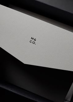 the logo for m & co is displayed on a black and white box with its lid open