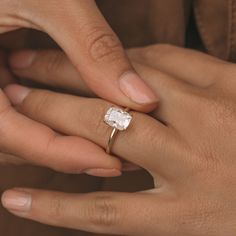 a man and woman holding hands with an engagement ring on their fingers, both wearing gold rings