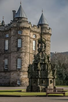 an old stone building with two towers and a bench in the foreground on a cloudy day