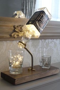 a lamp that is sitting on top of a wooden table next to glasses and a mirror