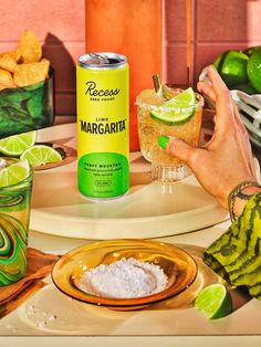 a can of margarita sitting on top of a table next to two glasses filled with limeade