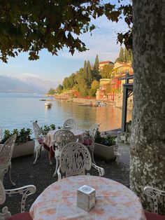 an outdoor dining area with tables and chairs overlooking the water