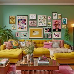 a living room filled with yellow couches and lots of pictures on the wall above them