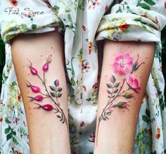 two women's legs with tattoos on them, one has flowers and the other has leaves