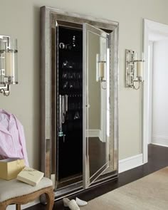 a room with a chair, mirror and jewelry cabinet in the corner on the wall