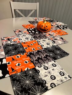 a table topped with halloween place mats and a pumpkin sitting on top of one of them