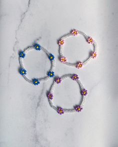 These cheerful floral bracelets are perfect for spring and summer! They're made with an elastic cord that allows them to easily slip on and off. This style is made from clear beads with your choice of pink, purple, blue or white flowers. If you need a different size or would like to customize the colors, just message me! Summer Flower Beaded Bracelets, White Beaded Bracelets With Flower Charm For Spring, Flower-shaped Beaded Bracelets For Beach, Spring White Beaded Bracelets With Flower Charm, Flower Shaped Beaded Bracelets For Beach In Spring, Spring Beach Beaded Bracelets With Flower Shape, Spring Flower Beaded Bracelets For Beach, Floral Beaded Bracelets For Beach And Spring, White Stretch Bracelet For Beach Spring Season