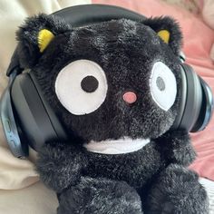 a black teddy bear wearing headphones on top of a bed