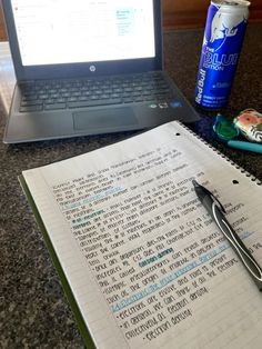 an open notebook sitting on top of a table next to a laptop computer and pen