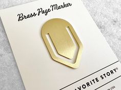 the brass brooch is sitting on top of a piece of paper that says brass page marker