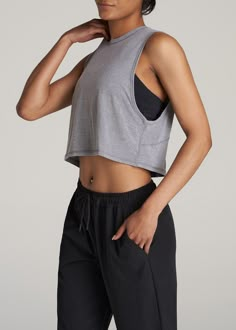 About Our Women's Tall Cropped Muscle Tank Having the right gear makes a difference. Everything about our athletic tank is made to help you smash your workout goals. Constructed with rayon and spandex, this tank won't slow you down. Our women's tall tank has been carefully crafted for women 5'9 to 6'6. Its cropped length ends just above the natural waist and its oversized armhole allows for maximum movement for a distraction-free workout. This athletic tank for tall women has been pre-washed and Exercise Shirts For Women, Muscle Tank Outfit Women, Fitted Tank Tops, Muscle Shirt Outfit Womens, Outfits For Muscular Women, Woman In Tank Top, Muscle Tank Outfit, Grey Tank Top Outfit, Sports Shirt Outfit