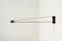 a wall mounted light with two lights attached to it's sides, in a white room