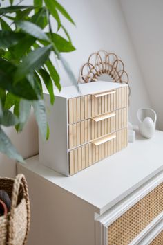 a white dresser topped with drawers next to a potted plant