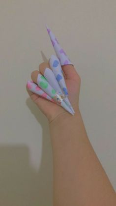 a person's hand holding three toothbrushes with pastel designs on them