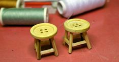 two wooden stools sitting on top of a table next to spools of thread