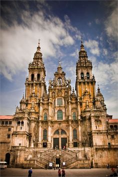 an old building with two towers and people standing in front