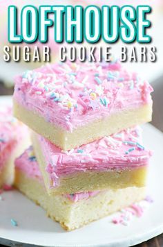 three sugar cookie bars with pink frosting and sprinkles stacked on top of each other