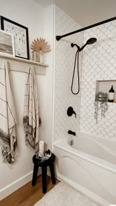 a white bathroom with black and white accessories on the shower head, rugs and towels