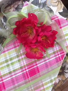 red flowers are sitting on top of a pink and green plaid tableclothed box