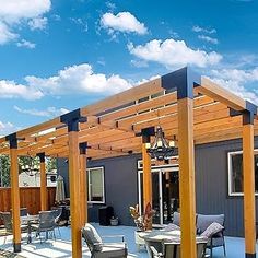 an outdoor patio with wooden pergols and chairs on it's side, under a blue sky with white clouds