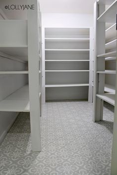 an empty walk - in closet with white shelving and gray floor tiles on the walls