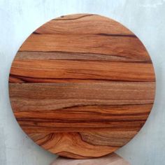 a round wooden cutting board sitting on top of a white counter next to a wall