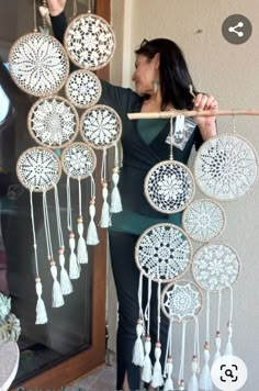 a woman is holding up some white crochet dream catchers