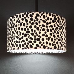 a leopard print lampshade hanging from a black wall with white spots on it