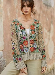 a woman standing in front of a wall wearing a jacket with flowers on the back