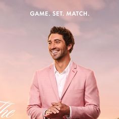 a man in a pink suit is smiling and standing with his hands on his chest