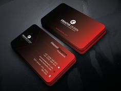 two red and black business cards sitting on top of a dark surface with the letter g