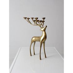 a golden deer figurine with four candles in it's antlers on a white surface