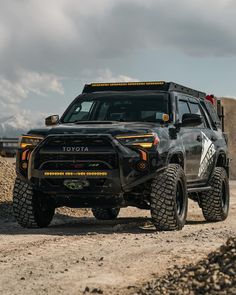 a black toyota truck driving down a dirt road