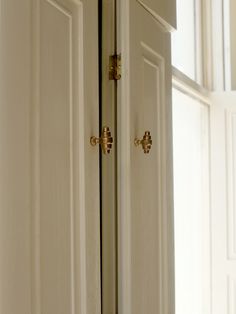 an open white door with brass handles and knobs