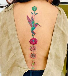 the back of a woman's neck with a hummingbird and flowers on it