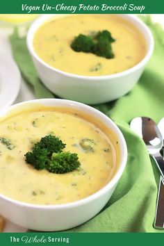 two bowls of broccoli cheese soup with silver spoons