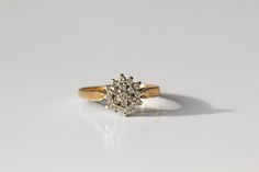 a diamond cluster ring sitting on top of a white surface