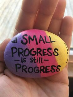 a hand holding a rock that says small progress is still progress